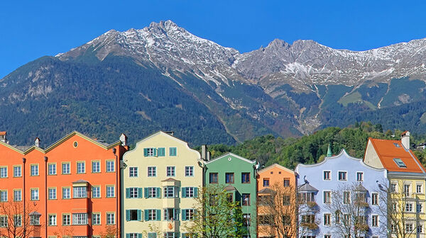 Die Häuserfassaden am Inn beeindrucken mit ihrer traditionellen Architektur und farbenfrohen Gestaltung, die eine attraktive Szenerie vor dem Bergpanorama schaffen.