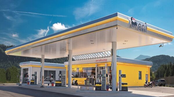 Eni Tankstelle mit Zapfsäulen, Waschanlage und Shop. Im Hintergrund blauer Himmel und Berge.