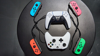 Ein Playstation, ein Xbox und 4 Switch Controller aufgelegt auf einem schwarzen Tisch.