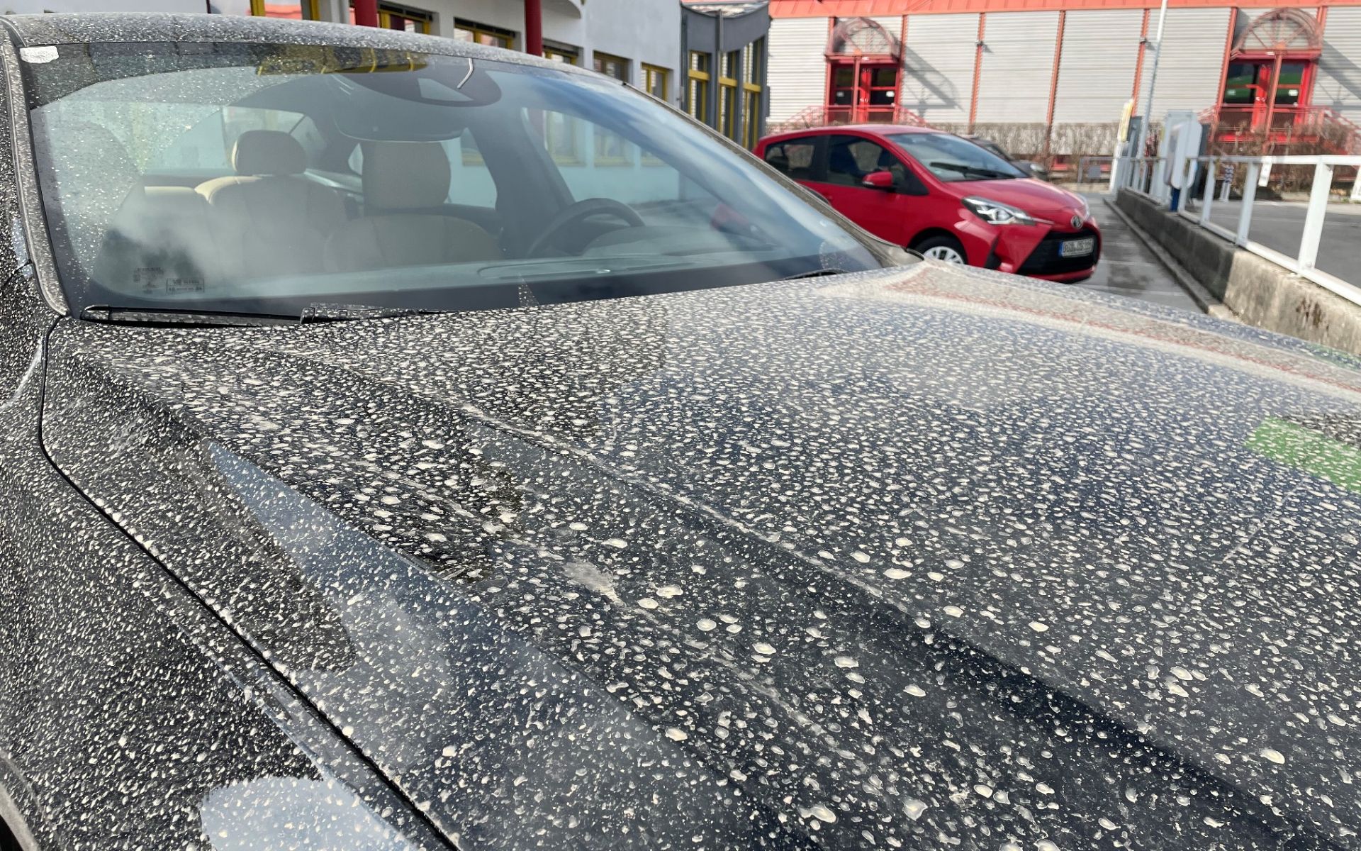 Saharastaub auf der Motorhaube von einem schwarzen Auto.