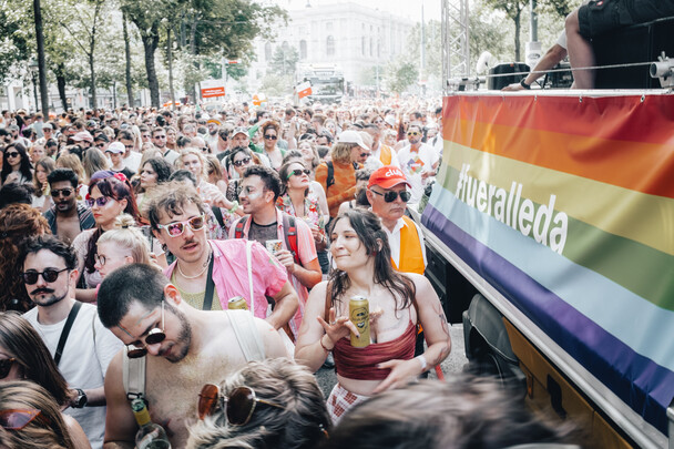 ÖAMTC auf der Regenbogenparade 2023 Das Foto zeigt viele Menschen auf der Regenbogenparade, die neben den ÖAMTC Auto gehen. Am Rechten Rand des Bildes ist ein Banner mit der Aufschrift "Für alle da" zu sehen.
