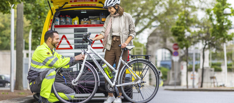 ÖAMTC-Pannenfahrer kontrolliert die Beleuchtung eines Fahrrades von einer jungen Radfahrerin.