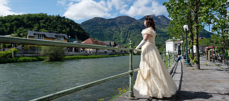 Frau im Sisi-Kostüm blickt auf den Fluss Traun.