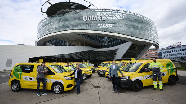 ÖAMTC Pannenfahrzeuge stehen aufgefächert vor dem ÖAMTC Gebäude in Wien Erdberg. Personen stehen bei den Fahrzeugen.