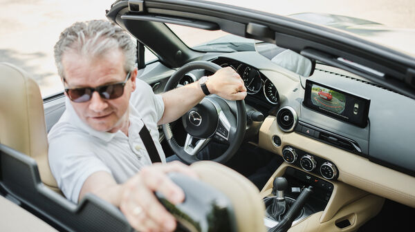 Eine Person fährt in einem Cabrio retour und blickt deshalb zurück.