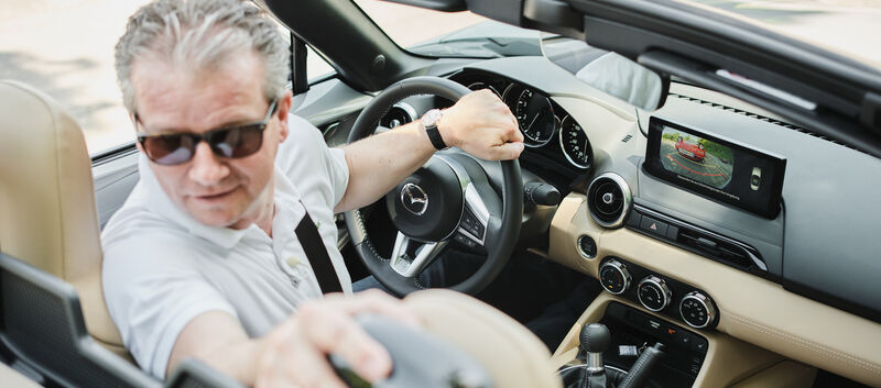 Eine Person fährt in einem Cabrio retour und blickt deshalb zurück.