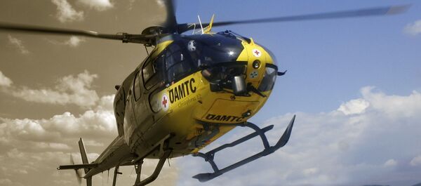 ÖAMTC Hubschrauber im Flug. Im Hintergrund Himmel mit Wolken. Die linke Hälfte des Bildes ist in Schwarz-Weiß ist.