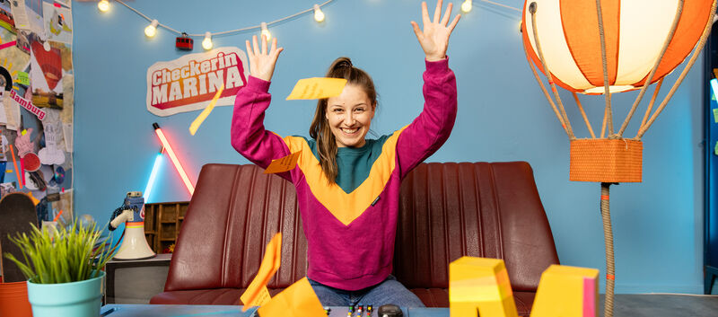 Marina Blanke sitzt am Sofa im Checker-Studio.