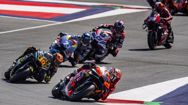 Eine Gruppe von Rennfahrern auf Motorrädern fährt schnell über die Strecke.
