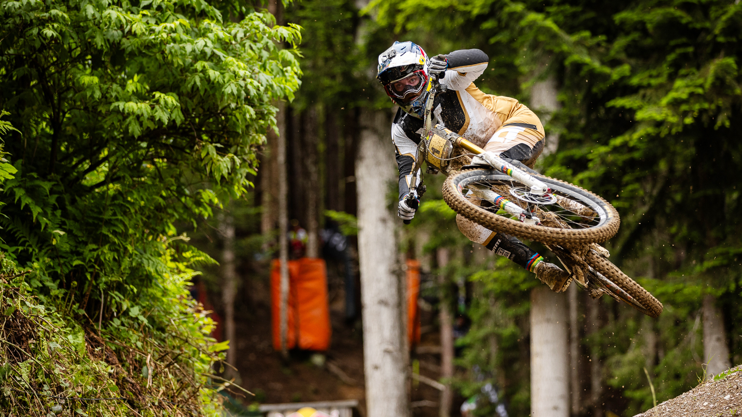 Mountainbike-Profi Vali Höll im Sprung auf einer Downhill-Strecke im Wald.