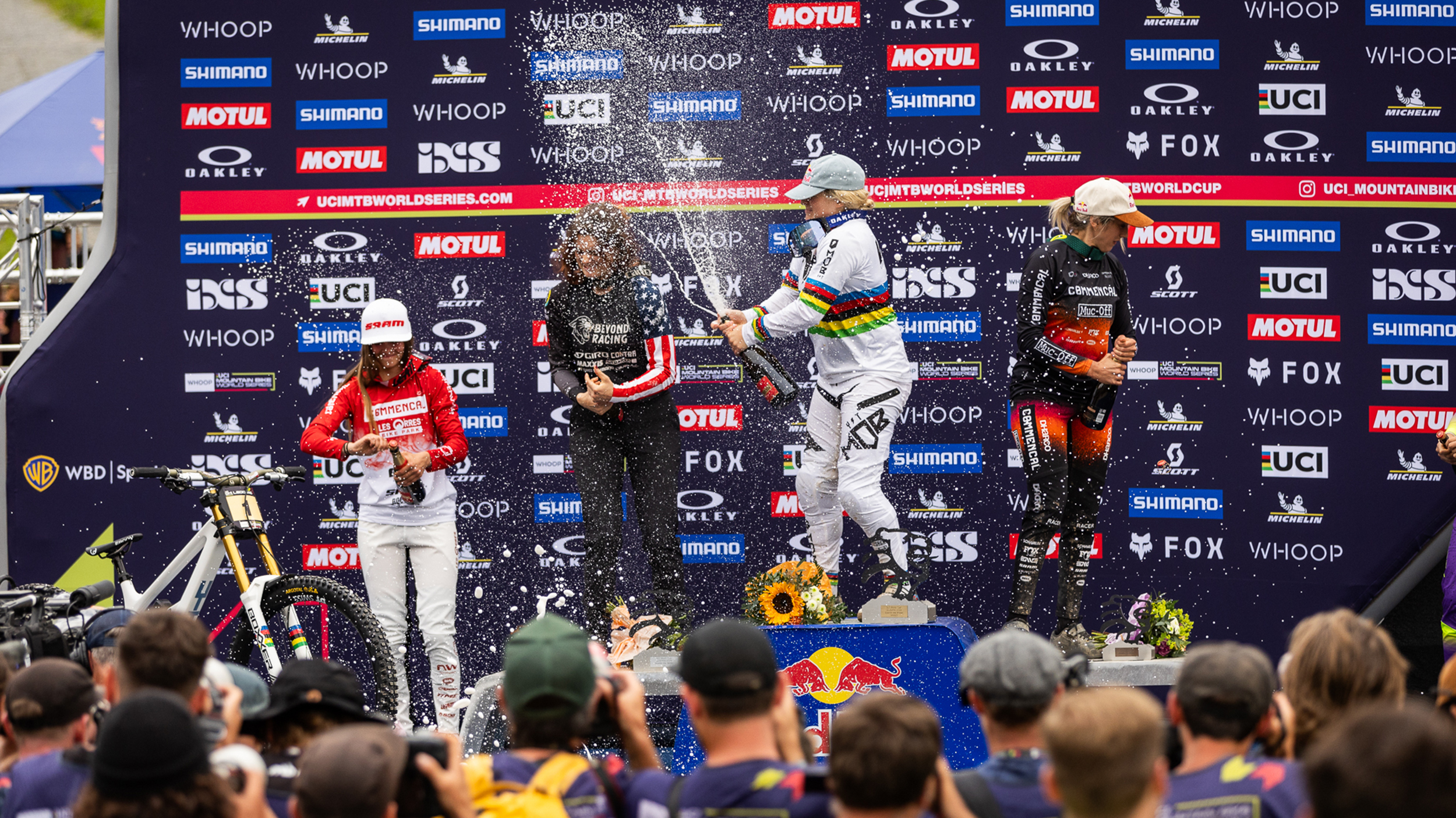 Downhill-Mountainbikerin Vali Höll spritzt vom Siegespodest aus Champagner in die Menge.