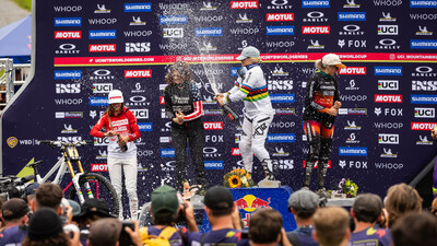 Downhill-Mountainbikerin Vali Höll spritzt vom Siegespodest aus Champagner in die Menge.