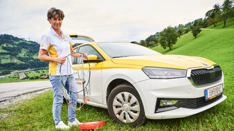Hauskrankenpflegerin Heidi Aschacher steht vor ihrem Auto und hält fürs Foto Schneeketten in der Hand.