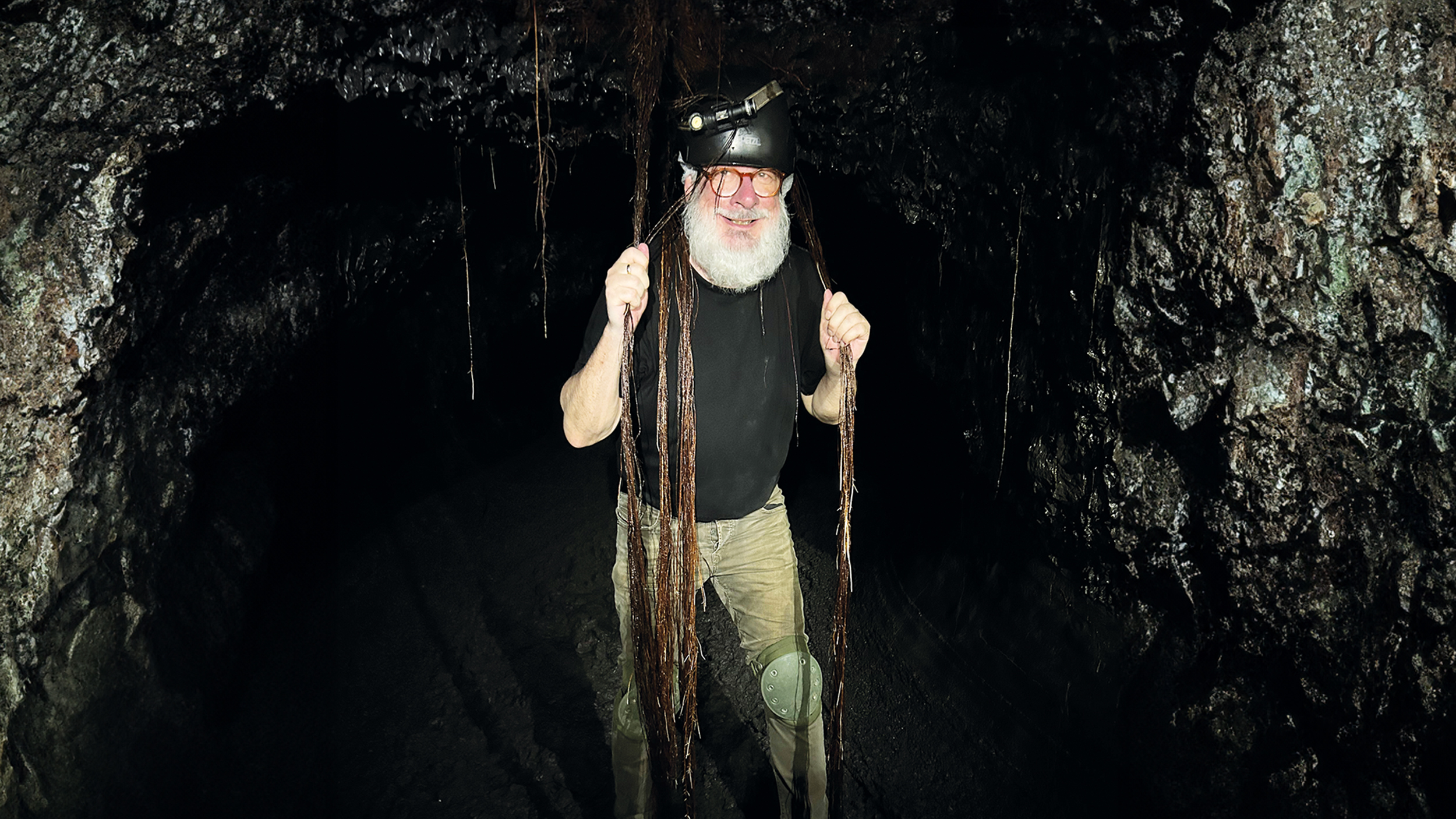 Mann mit Bart und Helm steht in einer dunklen Höhle