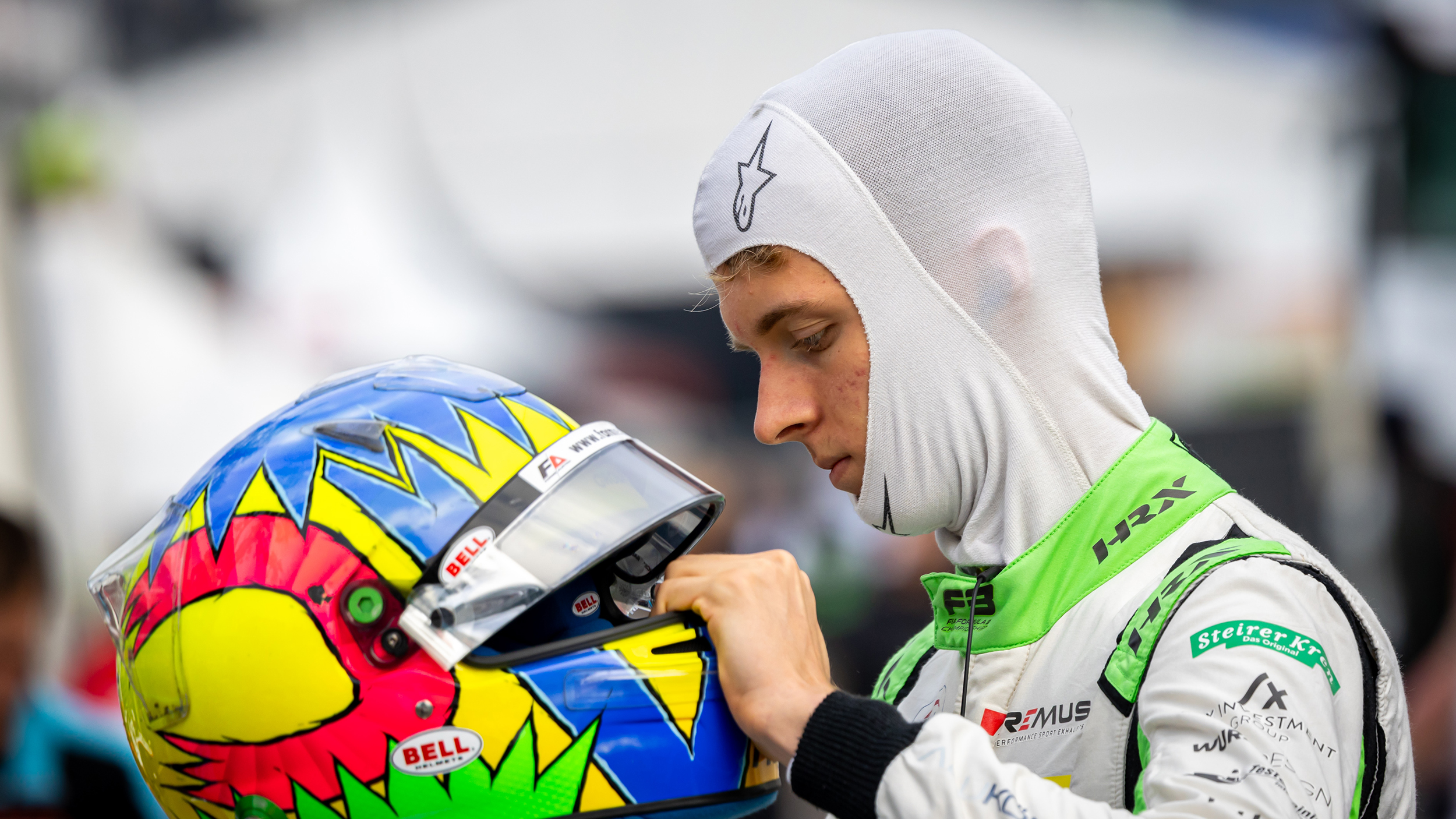 Der junge Rennfahrer Charlie Wurz sitzt sich seinen Helm auf.