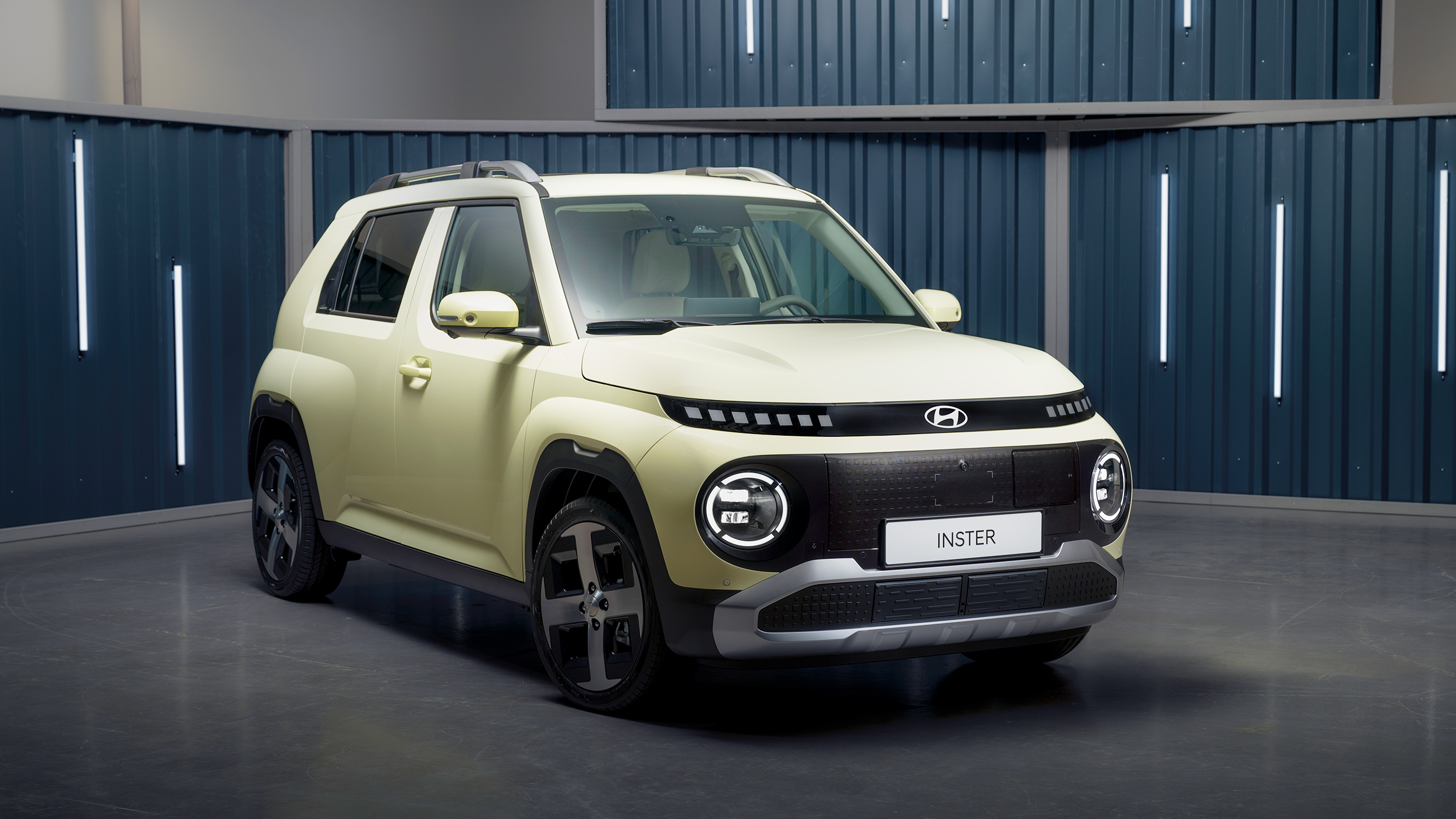 Ein blassgelbes Auto vor einem blauen Hintergrund mit Leuchtröhren