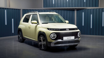 Ein blassgelbes Auto vor einem blauen Hintergrund mit Leuchtröhren