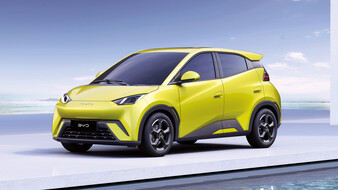 Ein neongelbes Auto auf einer weißen Plattform umgeben von Wasser