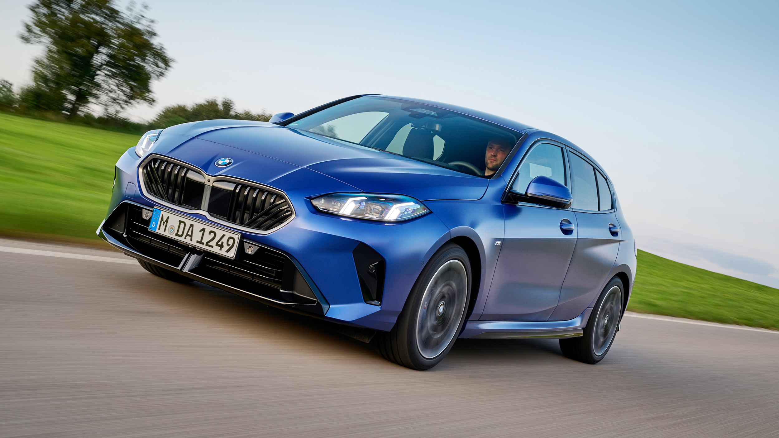 Ein blaues Auto fährt über eine Landstraße.