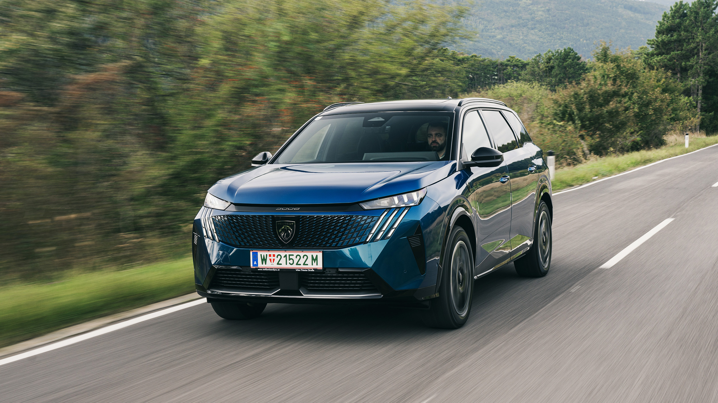 Ein blaues SUV fährt auf einer Landstraße