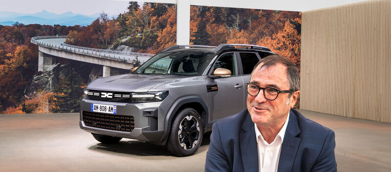 Dacia-CEO Denis Le Vot. Im Hintergrund steht ein graues SUV in einem Studio.