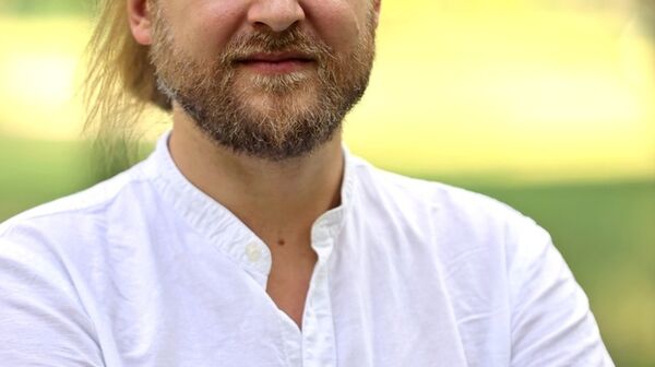 Das Bild ist ein Portraitfoto von Michael Szemes. Er trägt ein weißes Hemd und verschränkt die Arme. Der Hintergrund ist grün.