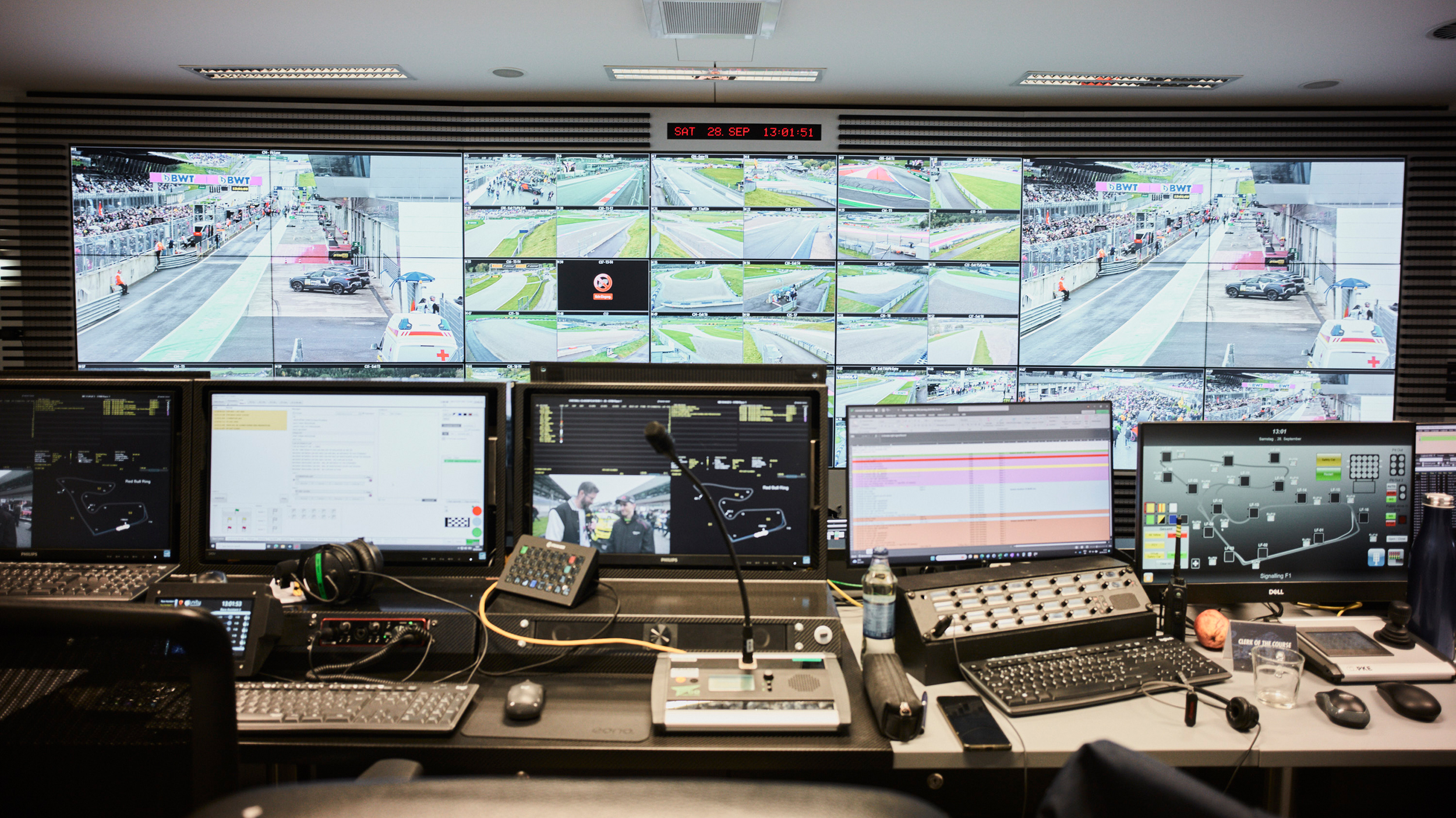 Der Race-Controll-Room des Red Bull Rings mit einer Wand voller Bildschirme, im Vordergrund befinden sich viele Laptops und Tastaturen. 