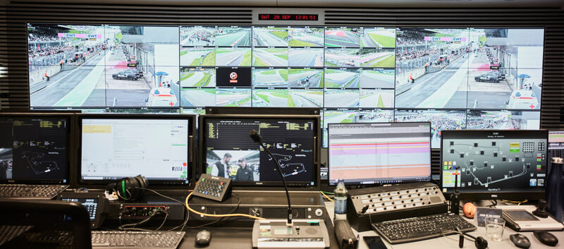 Der Race-Controll-Room des Red Bull Rings mit einer Wand voller Bildschirme, im Vordergrund befinden sich viele Laptops und Tastaturen.