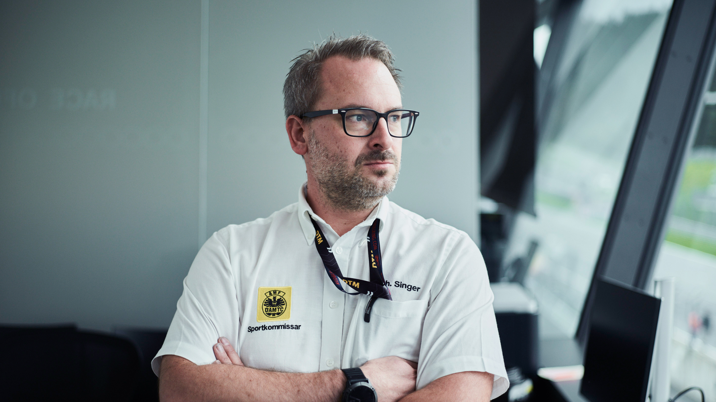 Ein Sportkommissar blickt durch eine große Fensterfront auf den Red Bull Ring.