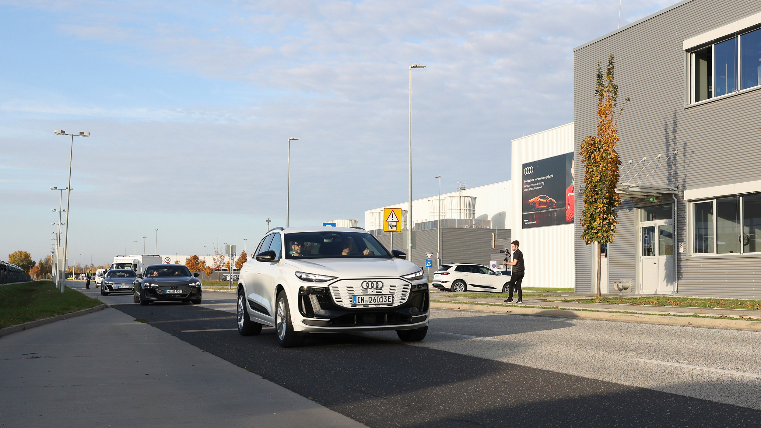 Ein weißer Audi fährt an einem grauen Gebäude vorbei