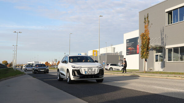 Ein weißer Audi fährt an einem grauen Gebäude vorbei