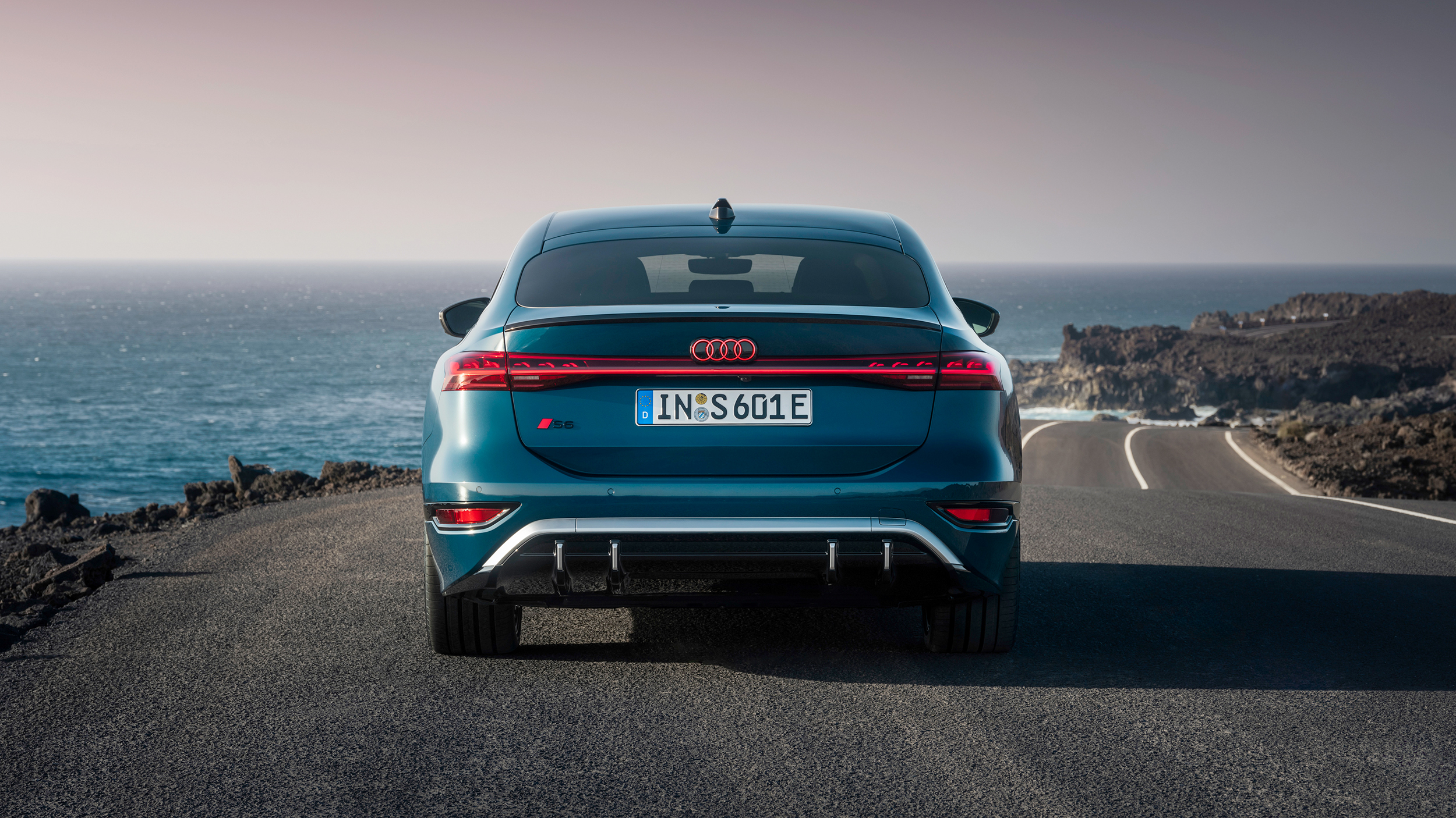 Das Heck eines blauen Audi am Meeresufer