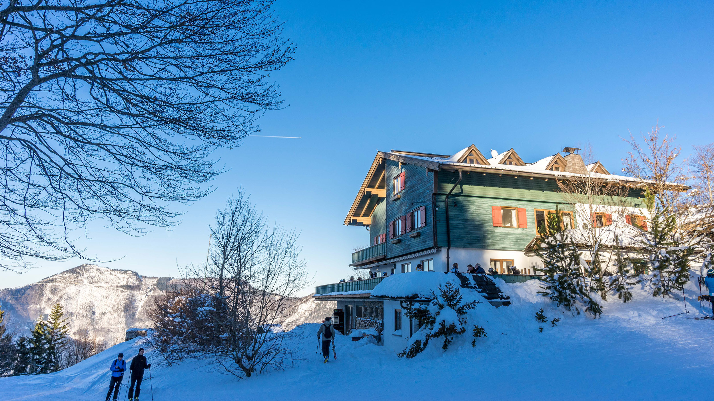 Das Hotel Hochberghaus am Kasberg umgeben von Bergen und einer Schneelandschaft.
