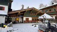 Außenaufnahme des Hotels Hochberghaus am Kasberg in Grünau im Almtal. Zu sehen sind drei Gebäude, davor liegen Ski im Schnee.