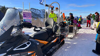 Im Vordergrund steht ein Ski-Do bei der Bergstation am Kasberg. Er ist mit einem Anhänger fürs Gepäck ausgestattet.