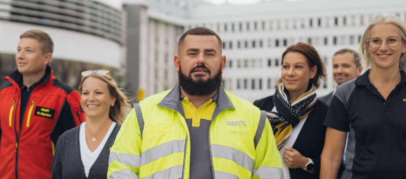 Sechs ÖAMTC Mitarbeiter und Mitarbeiterinnen gehen gemeinsam vor dem Mobilitätszentrum auf die Kamera zu.