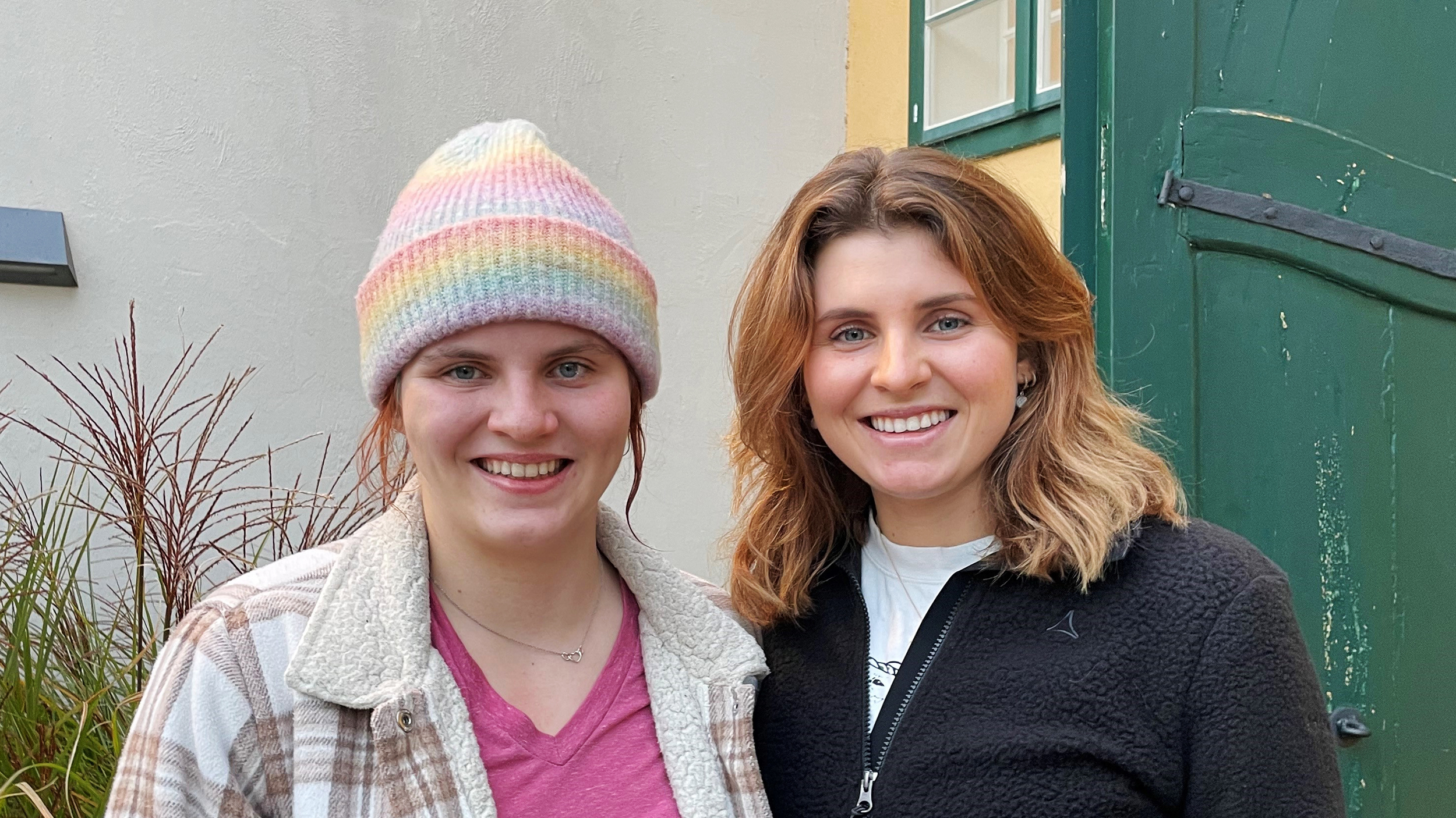 Zwei Frauen, eine mit Haube, stehen vor einem Haus. Es sind die Parasportlerinnen Vroni und Elisabeth Aigner.