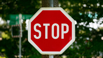 Ein Stoppschild, im Hintergrund eine Hecke
