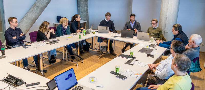 Konferenz der auto touring-Redaktion: Mehrere Redakteure sowie Grafiker sitzen mit Laptops um einen weißen Tisch.