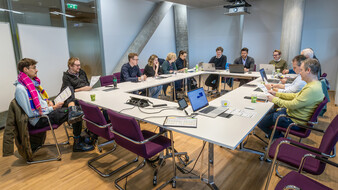 Konferenz der auto touring-Redaktion: Mehrere Redakteure sowie Grafiker sitzen mit Laptops um einen weißen Tisch.