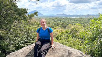 Redakteurin Verena Schauer auf Felsen, im Hintergrund grüne Landschaft.