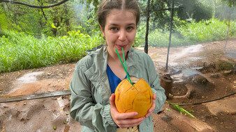 Redakteurin Verena Schauer trinkt mit einem Strohhalm aus einer orangenen Kokosnuss.