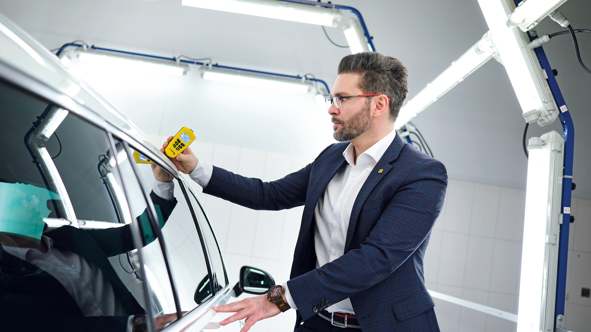 Michael Planer verwendet ein Lackschichtdichten-Messgerät an einem Auto