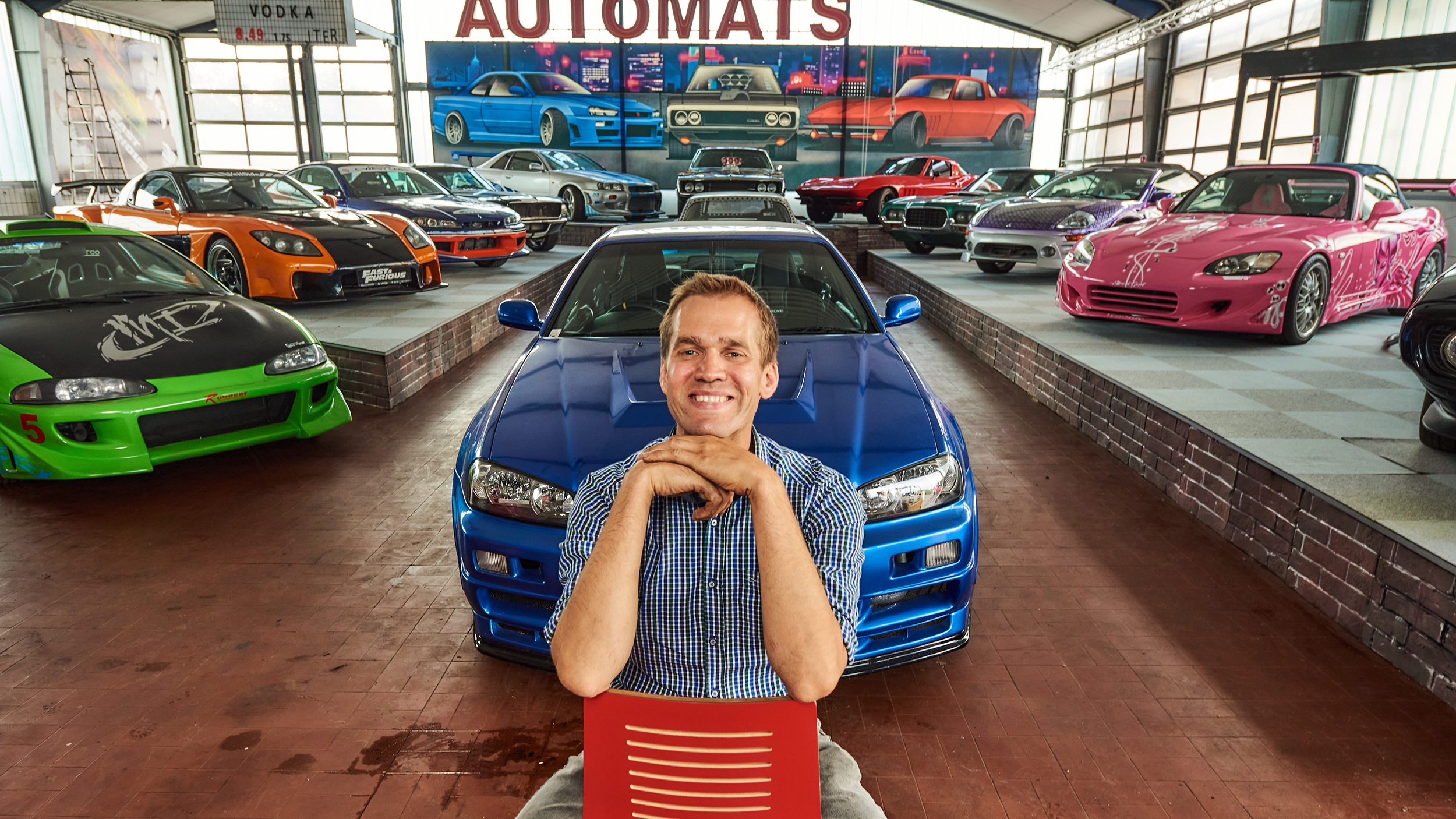 Martin Hahn sitzt vor Filmautos von "Fast an Furious".