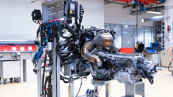 Ein Automobil-Motor steht auf einer Plattform in einer Halle.
