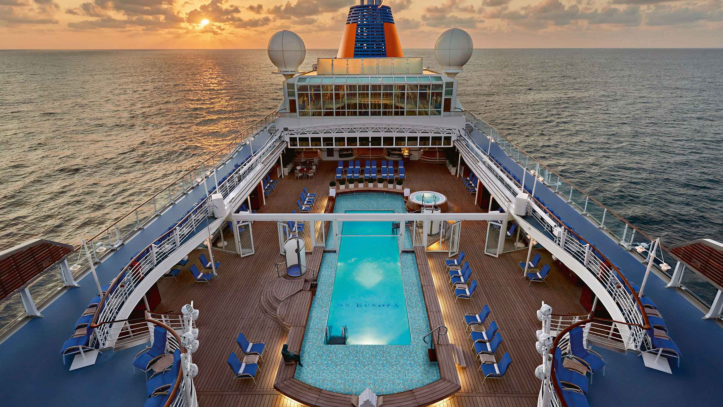 Zu sehen ist eine Ansicht des Decks der MS Europa von oben mit Blick auf das Pool bei Fahrt auf hoher See.