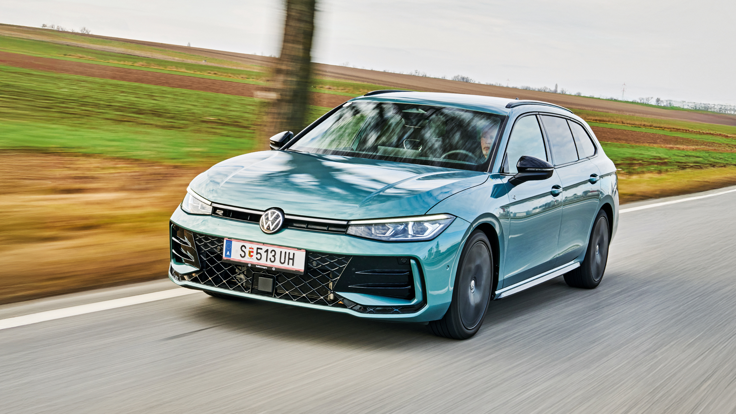 Blauer VW Passat auf Landstraße. Man sieht die Front der Autos. 