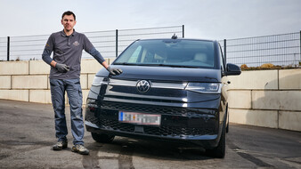 Der mobile Dellendrücker Andreas Winklmair steht am Parkplatz neben seinem schwarzen VW Multivan. Seine Hand liegt auf der Motorhaube.