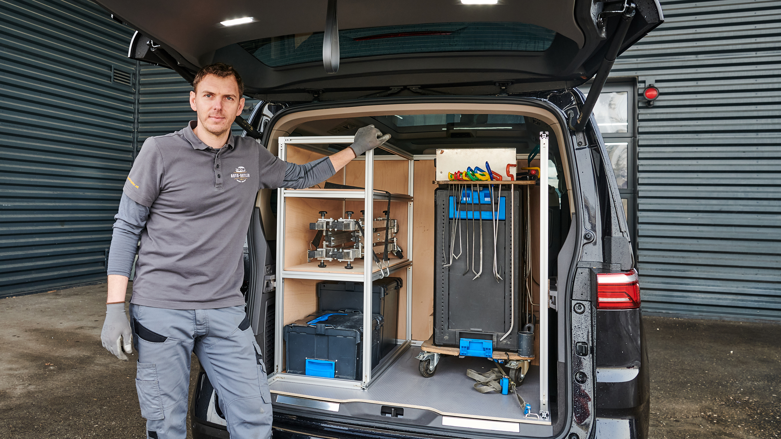 Der mobile Dellendrücker Andreas Winklmair steht vor dem offenen Laderaum seines VW Multivan, in dem Werkzeug zu sehen ist.