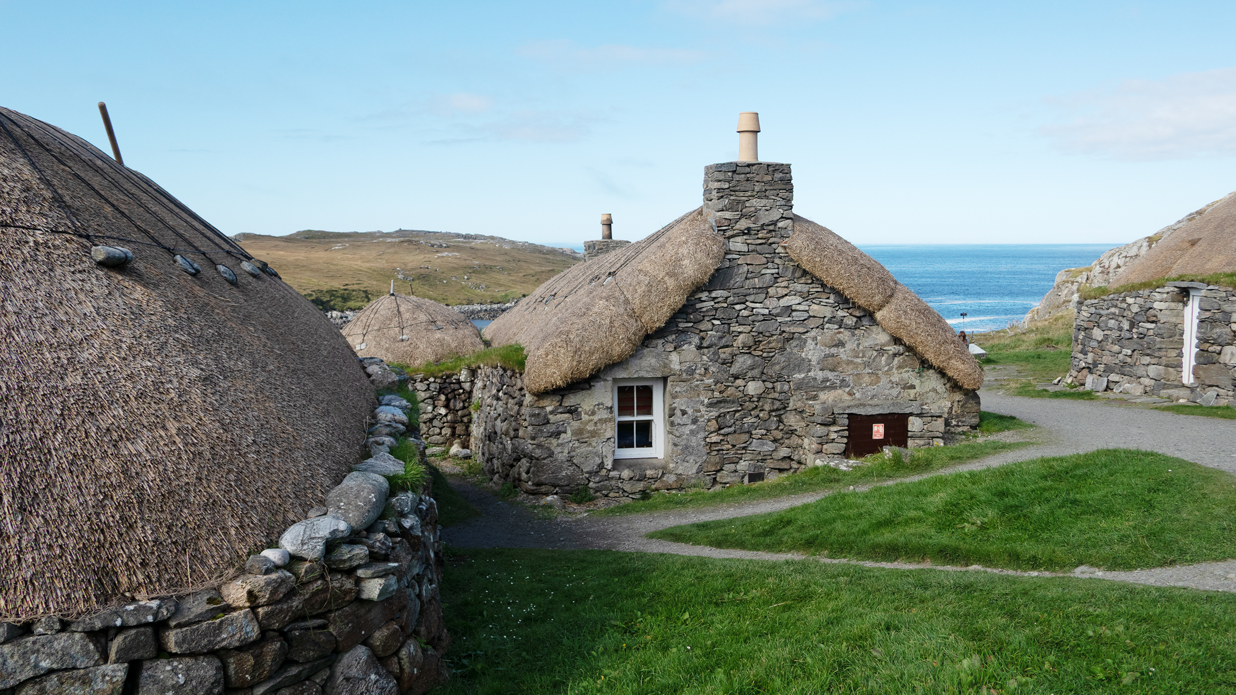 Typische Blackhouses auf den Äußeren Hebriden, im Hintergrund befindet sich das Meer.